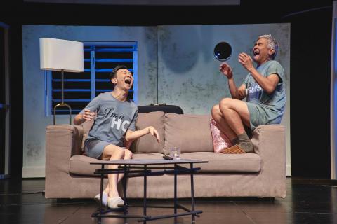 Image of Hossan Leong and Rody Vera in nightshirts laughing on a couch. Rody Vera is sitting on the edge.