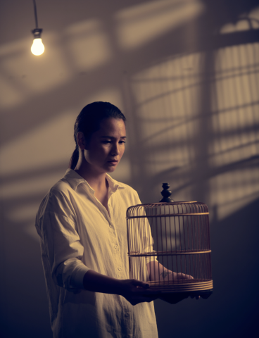Oo-woo publicity photo with cast member Isabella Chiam holding an empty bird cage