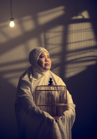 Oo-woo publicity photo with cast member Dalifah Shahril in white muslim woman prayer dress hugging an empty bird cage